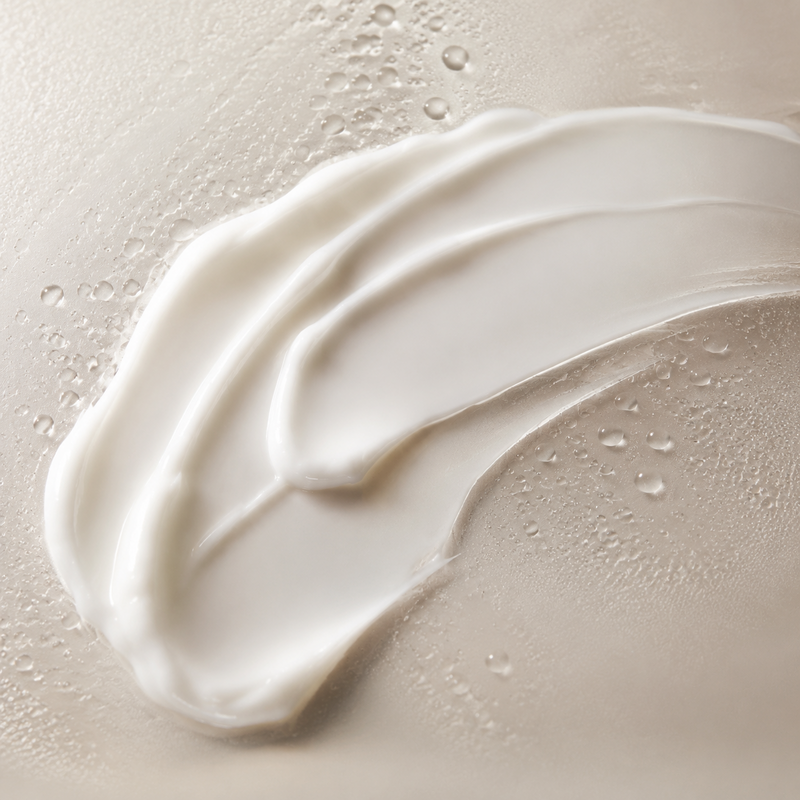 Creamy moisturizer texture with water droplets on frosted glass